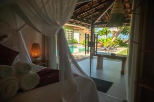 a bedroom with a bed and a view of a pool at Pousada Villa Tainá - Arraial d'Ajuda, Bahia in Arraial d'Ajuda