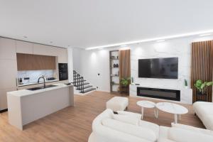 a kitchen and living room with white furniture and a tv at Aria Luxury Villa 2 in Dhërmi