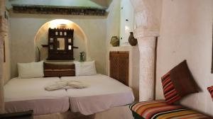 a bedroom with a bed and a chair in a room at Tenasbook Jnen Rayhane in Midoun
