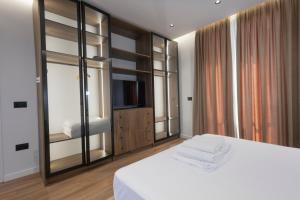 a bedroom with a white bed and a television at Aria Luxury Villa 2 in Dhërmi