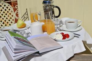 an open book on a table with coffee and a plate of fruit at The Coach House Denton in Grantham