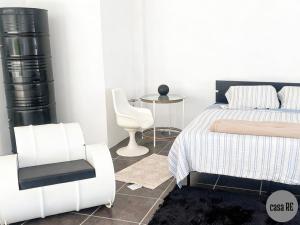 a white bedroom with a bed and a chair at Casa RE Completa in Tehuacán