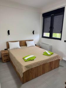 a bedroom with a large bed with green pillows on it at Bran Apartments in Star Dojran