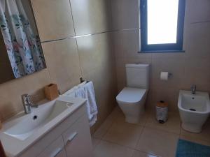 a bathroom with a sink and a toilet and a window at Maroiço Residence in Madalena