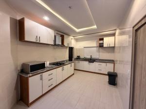 a large kitchen with white cabinets and a microwave at Luxury 3 Bedroom Duplex Service Aparment in Abuja in Abuja