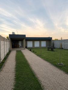 a house with a gravel driveway in front of a yard at Quincho Monoambiente Con Parrilla in Balcarce