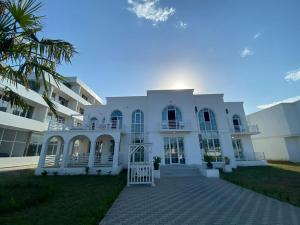 a white house with a palm tree in front of it at SAkura Hotel Astara in Astara
