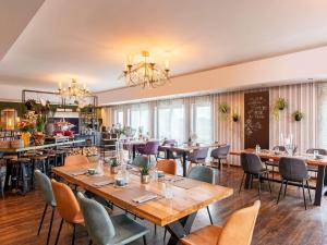 a restaurant with tables and chairs in a room at Mercure Hotel Bad Oeynhausen City in Bad Oeynhausen
