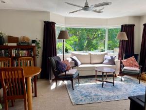 a living room with a couch and chairs and a table at Secluded Bush Retreat in Hikuai