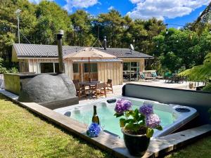 a swimming pool with a bottle of wine and purple flowers at Secluded Bush Retreat in Hikuai