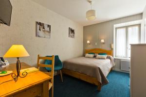 a bedroom with a bed and a desk with a desk at Hôtel Restaurant Au Pont de Raffiny in Saint-Romain