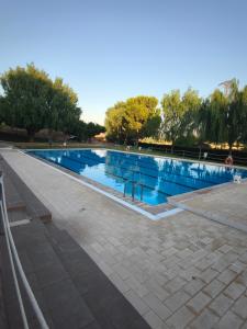 a swimming pool with blue water in a park at Apartamentos llerda in Cretas