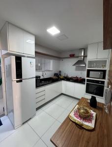 a kitchen with white appliances and a wooden table at Casa de Praia - Ipitanga in Lauro de Freitas