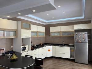 a kitchen with white cabinets and a table and a refrigerator at Villa cornich in Banzart