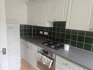 a kitchen with white cabinets and green tile on the wall at Ramsgate Cozy Home in Ramsgate