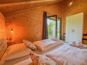 two beds in a wooden room with a window at Rattendorf 15B in Rattendorf