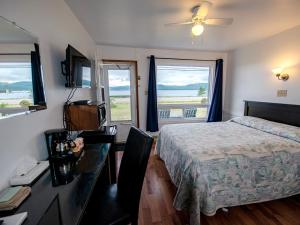 a bedroom with a bed and a desk and windows at Sea Breeze Motel in Ingonish +11 photos