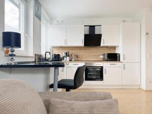 a kitchen with white cabinets and a black counter top at Am Berg und See in Stemwede