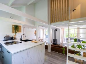 a kitchen with white counters and a large window at De Nordic Escape in Warmenhuizen