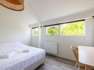a bedroom with a bed and a table and two windows at De Nordic Escape in Warmenhuizen