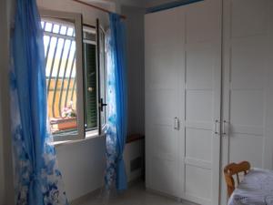 a bedroom with a window and blue curtains at Villetta Lucia in Sperlonga