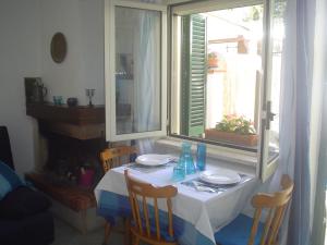 a table with a white table cloth and chairs and a window at Villetta Lucia in Sperlonga +4 photos