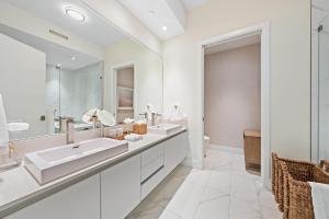 a white bathroom with two sinks and a mirror at Amrit Resort - Bask in Rare Oceanfront Luxury with Stunning Views in Riviera Beach
