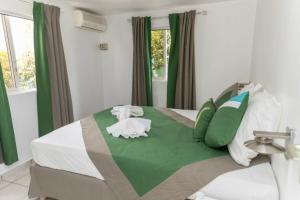 a bedroom with a large bed with green and white pillows at O baobab in Saint-François