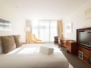 a hotel room with a bed and a flat screen tv at Novotel Canberra in Canberra