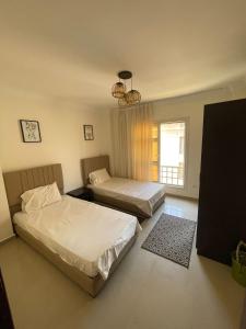 a bedroom with two beds and a window at شقه في مدينتي غرفتين و صاله مكيفه مفروشه فندقي - Fully Furnished & Air-Conditioned 2-Bedroom Apartment with Large Living Room in Madinaty - 98 sqm in Madinaty