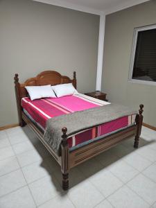 a bed with a wooden frame in a bedroom at I Love Tanque in Caculi