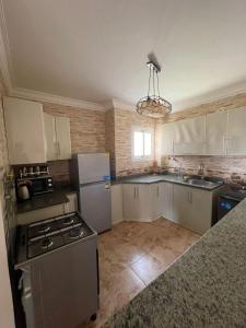 a kitchen with a stove and a refrigerator at شقه في مدينتي غرفتين و صاله مكيفه مفروشه فندقي - Fully Furnished & Air-Conditioned 2-Bedroom Apartment with Large Living Room in Madinaty - 98 sqm in Madinaty