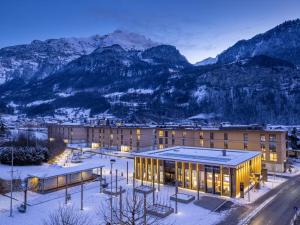 a building with snowy mountains in the background at Hotel Sherlock Holmes "nur 200 m zur Gondelbahn Hasliberg" in Meiringen