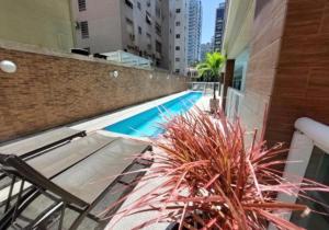 a swimming pool with chairs and a plant next to a building at Santos Unique 2701 Jacuzzi & Sea View Duplex in Santos