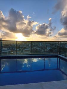 a swimming pool on top of a building with the sunset at Flat Aconchego Olinda - Vista e Piscina in Olinda