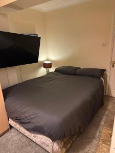 a bedroom with a bed and a flat screen tv at Heathrow Ensuite in West Drayton