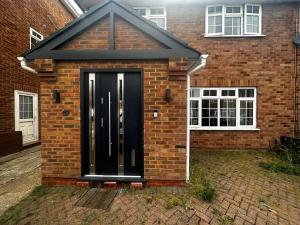 a black front door of a brick house at Heathrow Ensuite in West Drayton