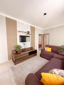 a living room with a couch and a flat screen tv at Casa Doce Lar 2 in Uberaba