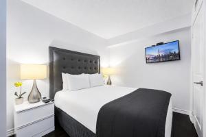 a bedroom with a large white bed with a black headboard at Altitude Suites on Yonge - Downtown Toronto Short Walk to SickKids, TMU & Eaton Centre in Toronto +22 photos