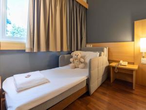 a teddy bear sitting on a bed in a room at ibis Paulinia in Paulínia