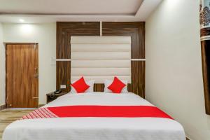 a bedroom with a large bed with red pillows at Hotel O White House in Patna