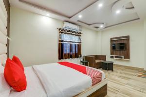 a bedroom with a bed with red pillows and a television at Hotel O White House in Patna +31 photos