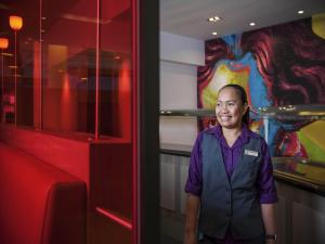 a woman is standing next to a red wall at Novotel Mechelen Centrum in Mechelen