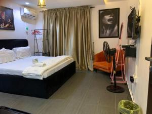 a bedroom with a bed and a chair and a television at Weltons Apartments in Ikeja