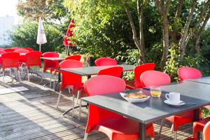 a row of tables and chairs with red chairs at Hôtel Les Gens De Mer Lorient by Popinns in Lorient