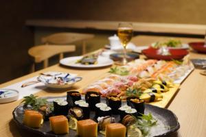 a table topped with different types of sushi and a glass of wine at THE SHIKAKA Hotel&Resort BUDOUNOKI in Itoshima