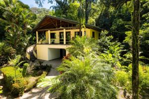 a yellow house in the middle of a garden at Casa Selva in Dominicalito