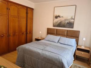 a bedroom with a bed with wooden cabinets and a painting at Ap Central 3 quartos com elevador e garagem in Pelotas