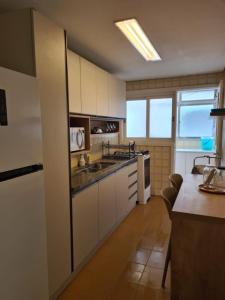 a kitchen with white cabinets and a counter top at Ap Central 3 quartos com elevador e garagem in Pelotas