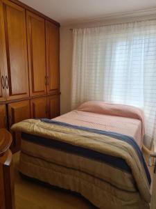 a small bedroom with a bed and a window at Ap Central 3 quartos com elevador e garagem in Pelotas +2 photos